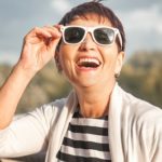 Mature woman wearing sunglasses while laughing and smiling