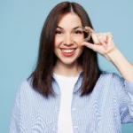 Woman smiling and holding Invisalign clear aligner